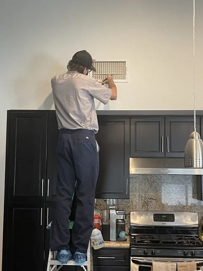 Technician inspecting an air vent during HVAC service in Scarsdale